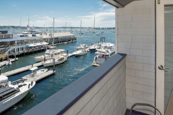 A balcony view overlooking a marina with several boats docked, under a clear blue sky.