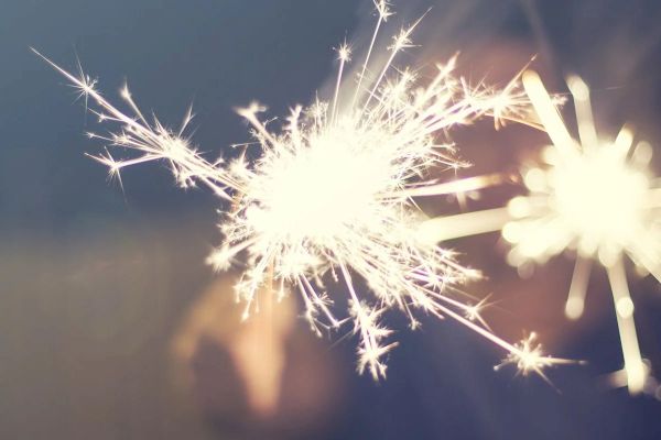 The image shows two bright sparklers burning against a dark background, creating a festive and vibrant display.