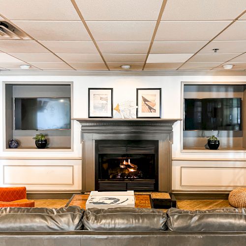 The image shows a cozy living room with a fireplace, two framed pictures above it, and books on the coffee table in front.