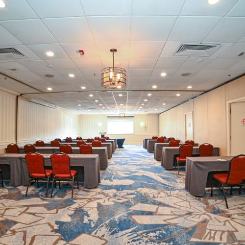 The image shows a conference room with rows of tables and chairs facing a lectern, set up for a meeting or presentation.