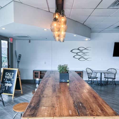 The image shows a modern café with a wooden table, industrial lights, wall art, and a "Salt" sign by the door.